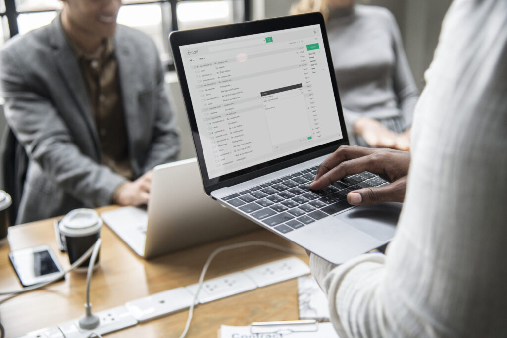 a real estate agent holding his computer and looking at email marketing tools